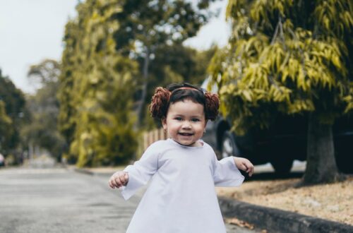 smiling baby girl wearing white dress standing on road