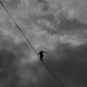 low angle photo grayscale of person tightrope walking