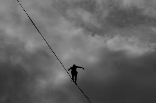 low angle photo grayscale of person tightrope walking